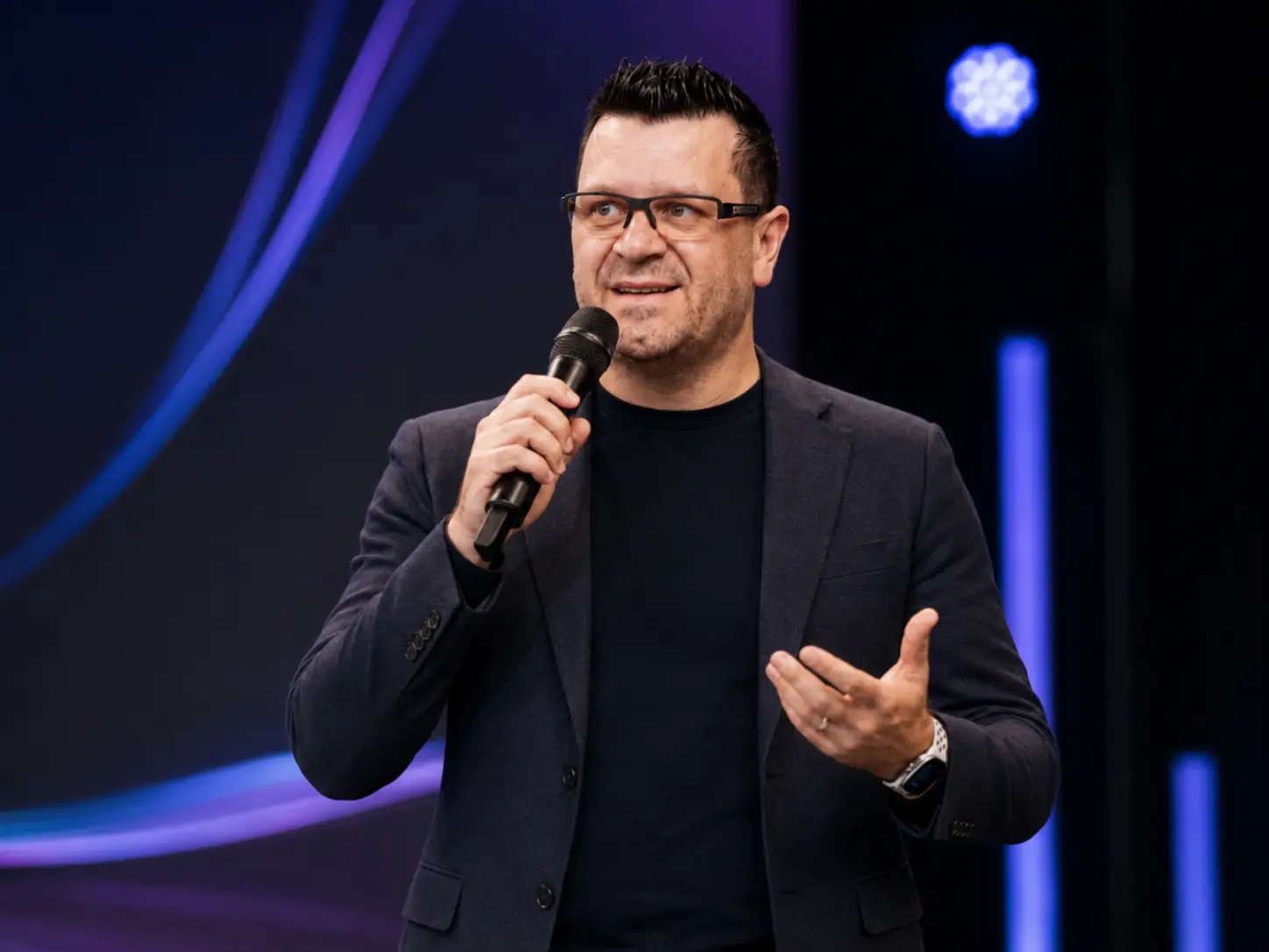Leandro Costa palestrando com microfone em evento presencial